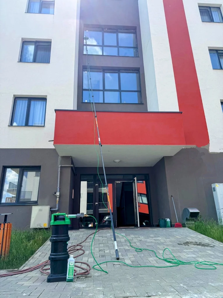 Curățarea geamurilor la etajele superioare ale unui bloc, cu tijă telescopică.