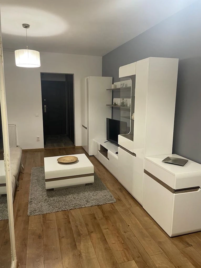 Living amenajat cu mobilier alb și parchet, după curățenia de întreținere.