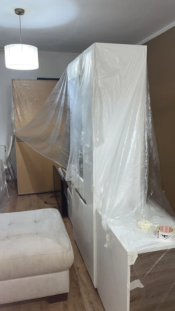 Mobilier protejat cu folie într-o locuință, pregătit pentru curățenie.