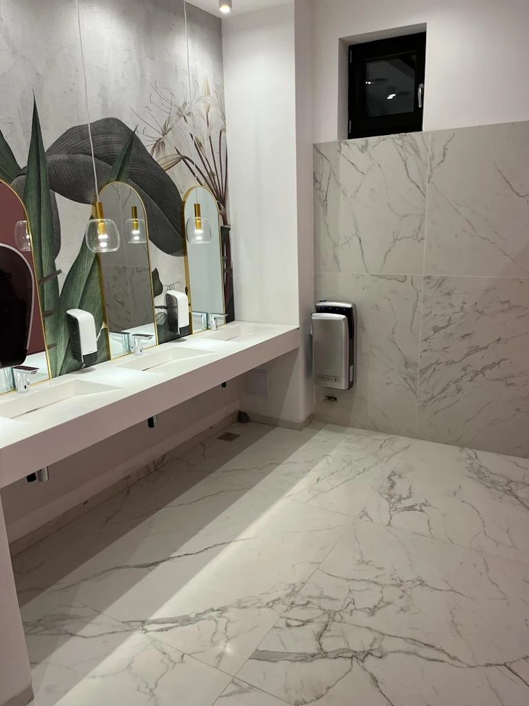 Spațiu sanitar comercial cu finisaje din marmură, oglinzi și suprafețe curate.